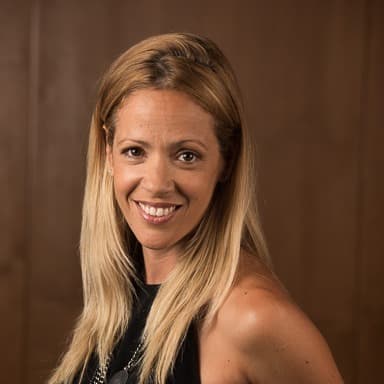 Romina Saaied, insurance advisor at We Insure Downtown Miami, smiling at the camera in front of a dark wood wall.