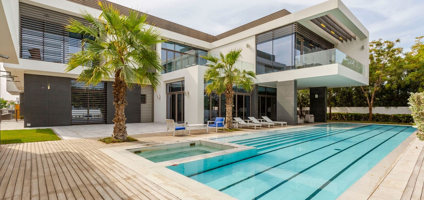 Modern white and gray house with a long pool and palm trees