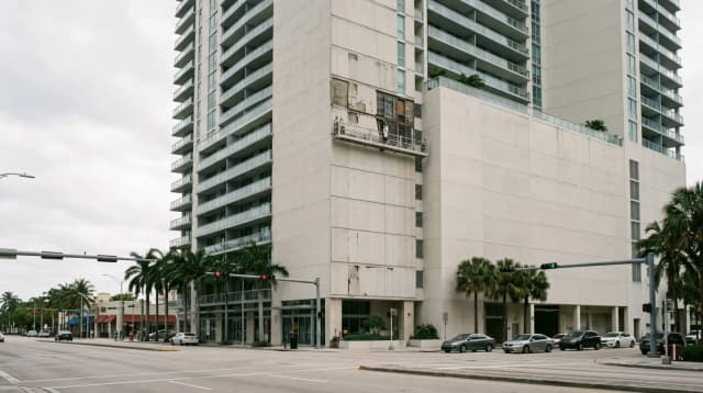 Una torre residenziale a Brickell, Miami, con una piattaforma sospesa su una delle facciate e una porzione del rivestimento rimossa per la riparazione.